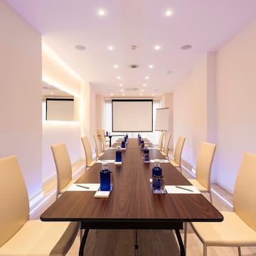 a long conference table with chairs and a projector screen
