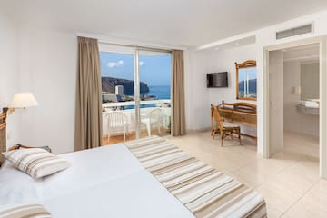 a room with a large bed and a balcony overlooking the ocean