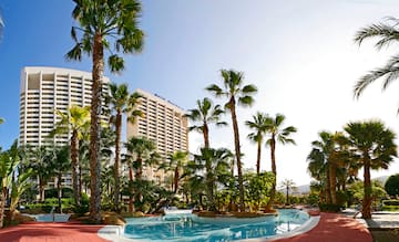 a pool with palm trees and a building in the background