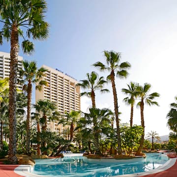 a pool with palm trees and a building in the background