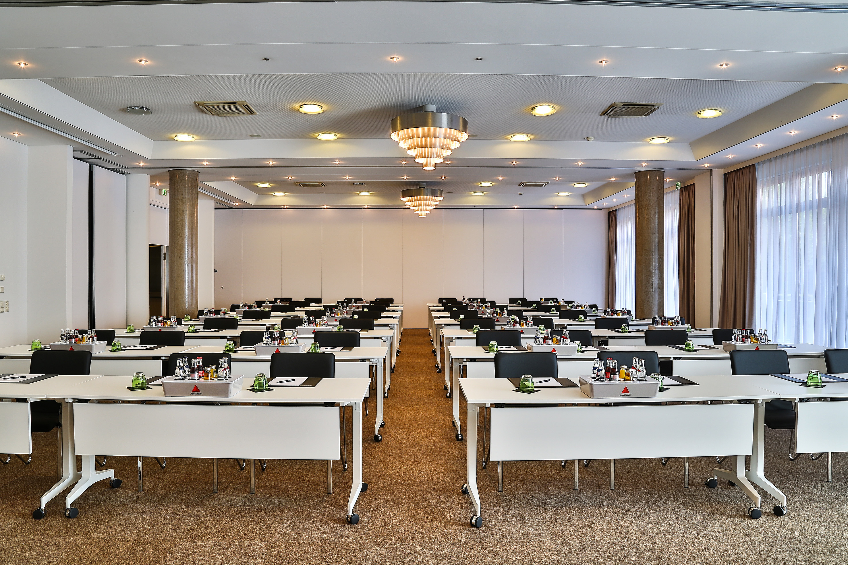 Prepared conference room with white tables, black chairs, and refreshments.