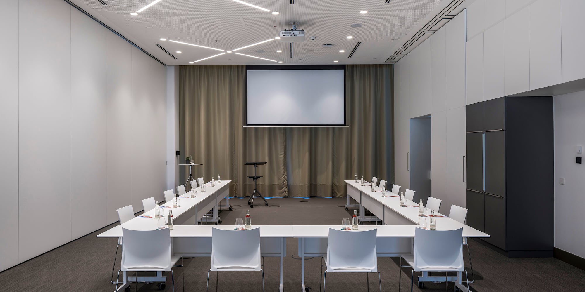 a room with a large screen and tables