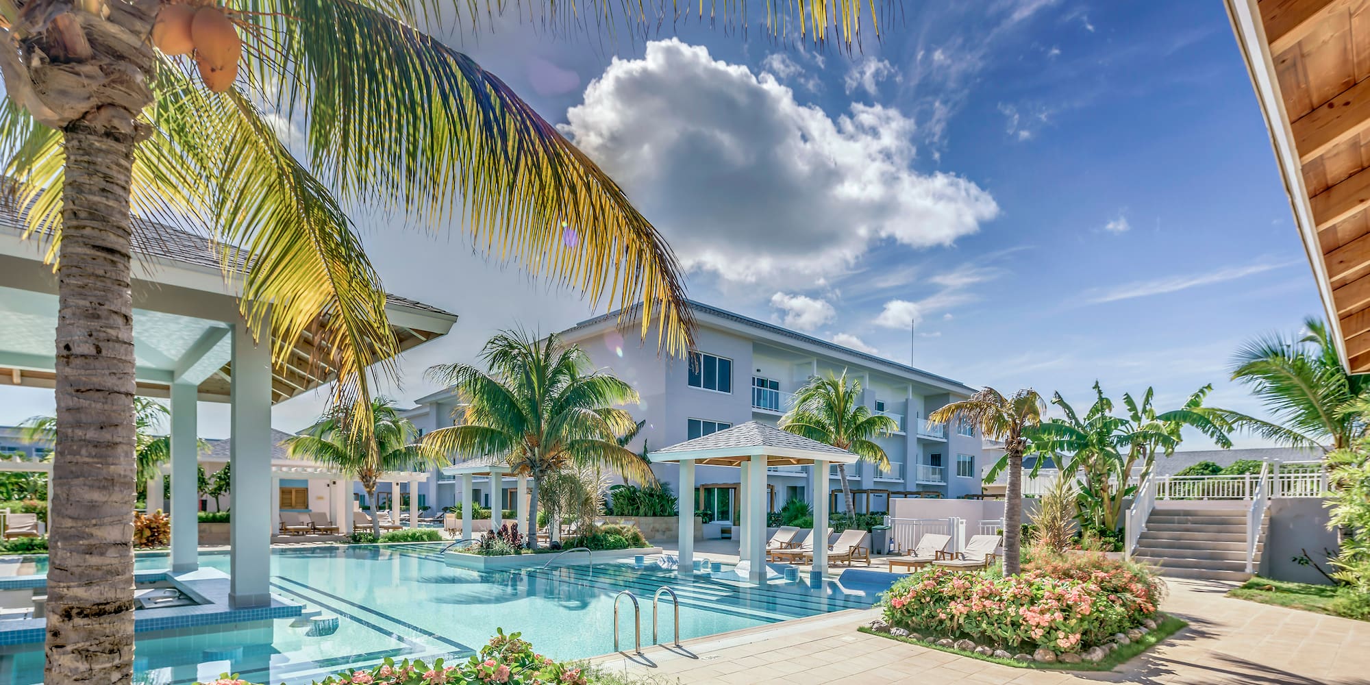 a pool with palm trees and a building with a blue sky