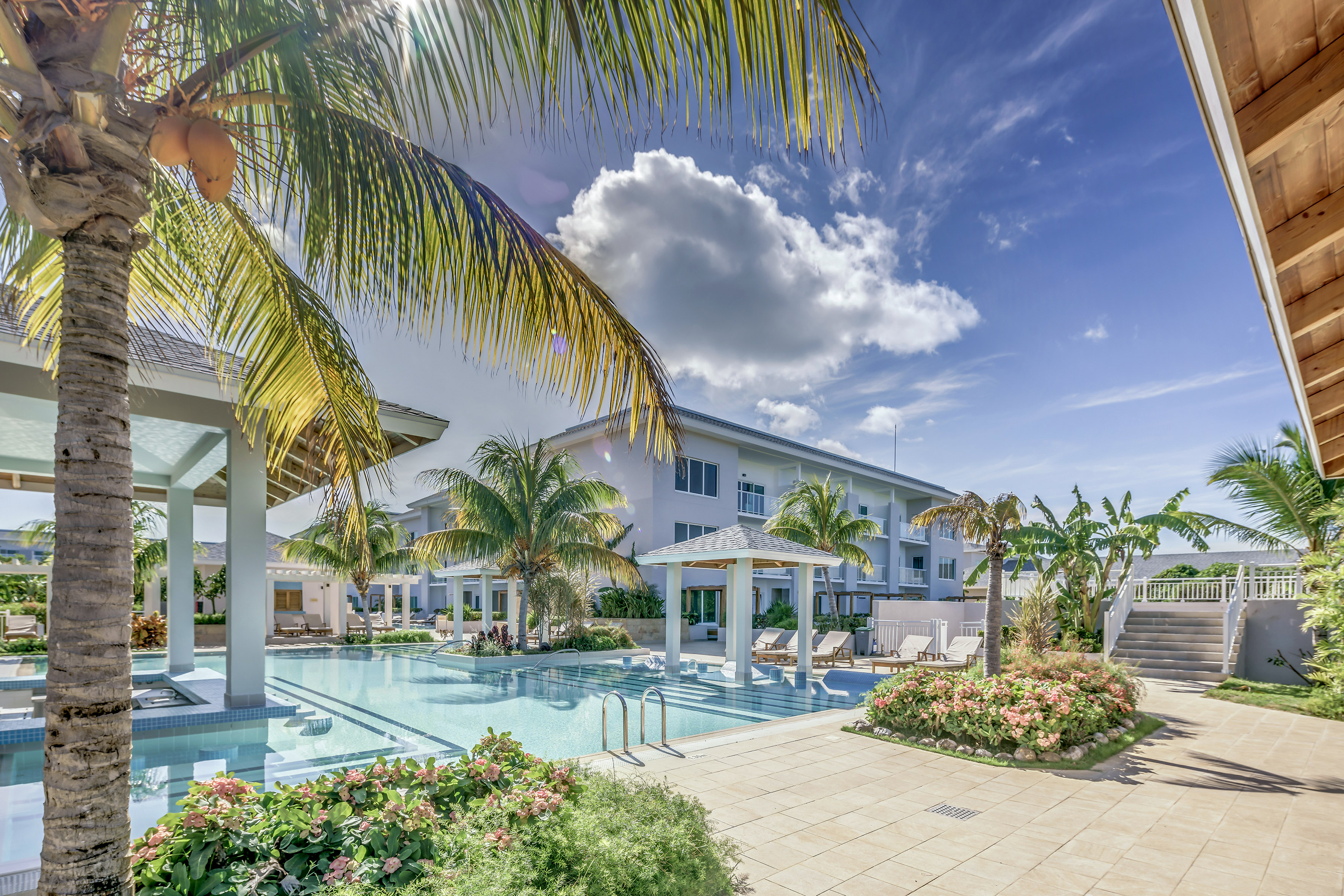 a pool with palm trees and a building with a blue sky