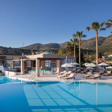 a pool with chairs and umbrellas by a building