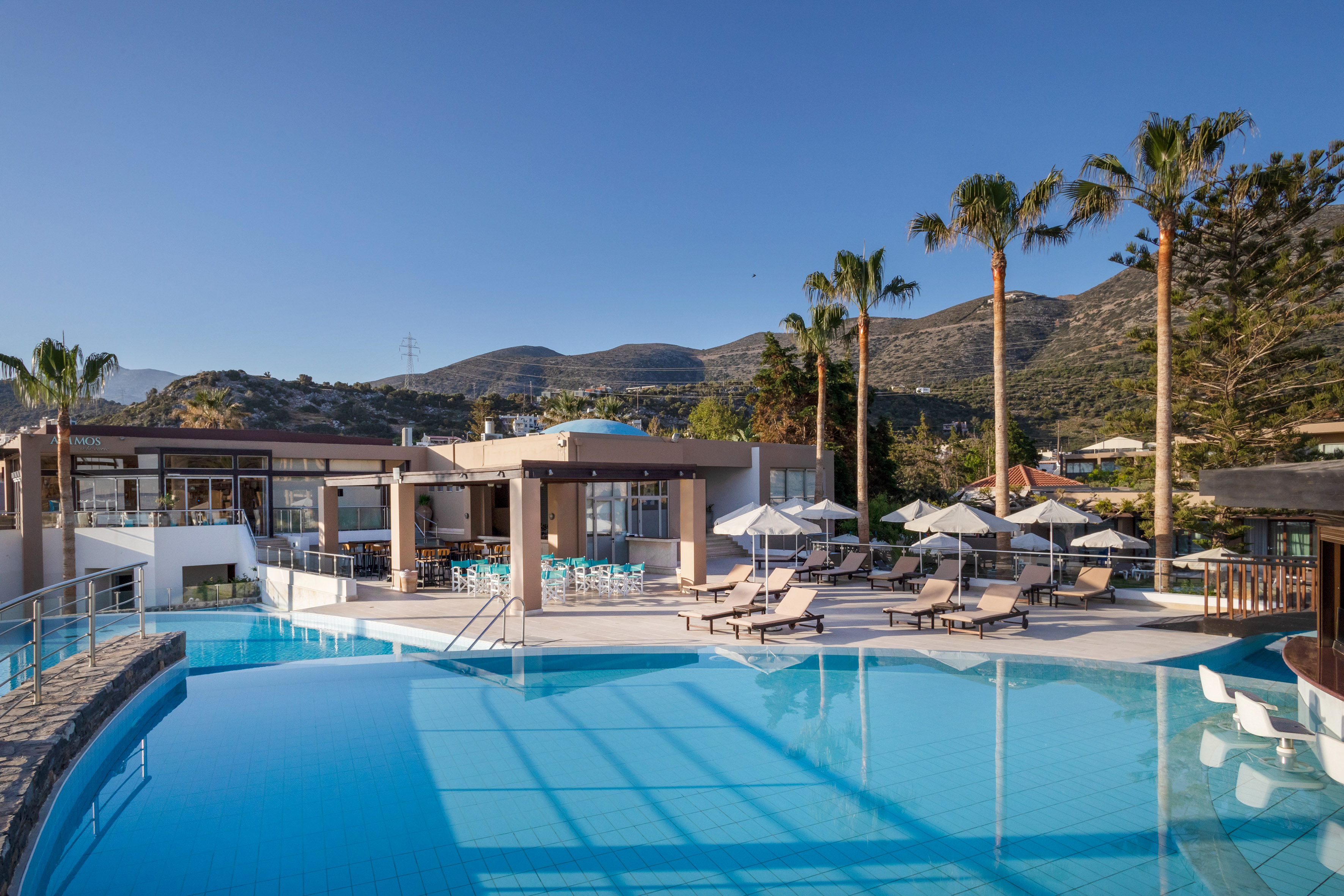 a pool with chairs and umbrellas by a building