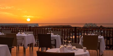 a table set up on a deck with a sunset in the background