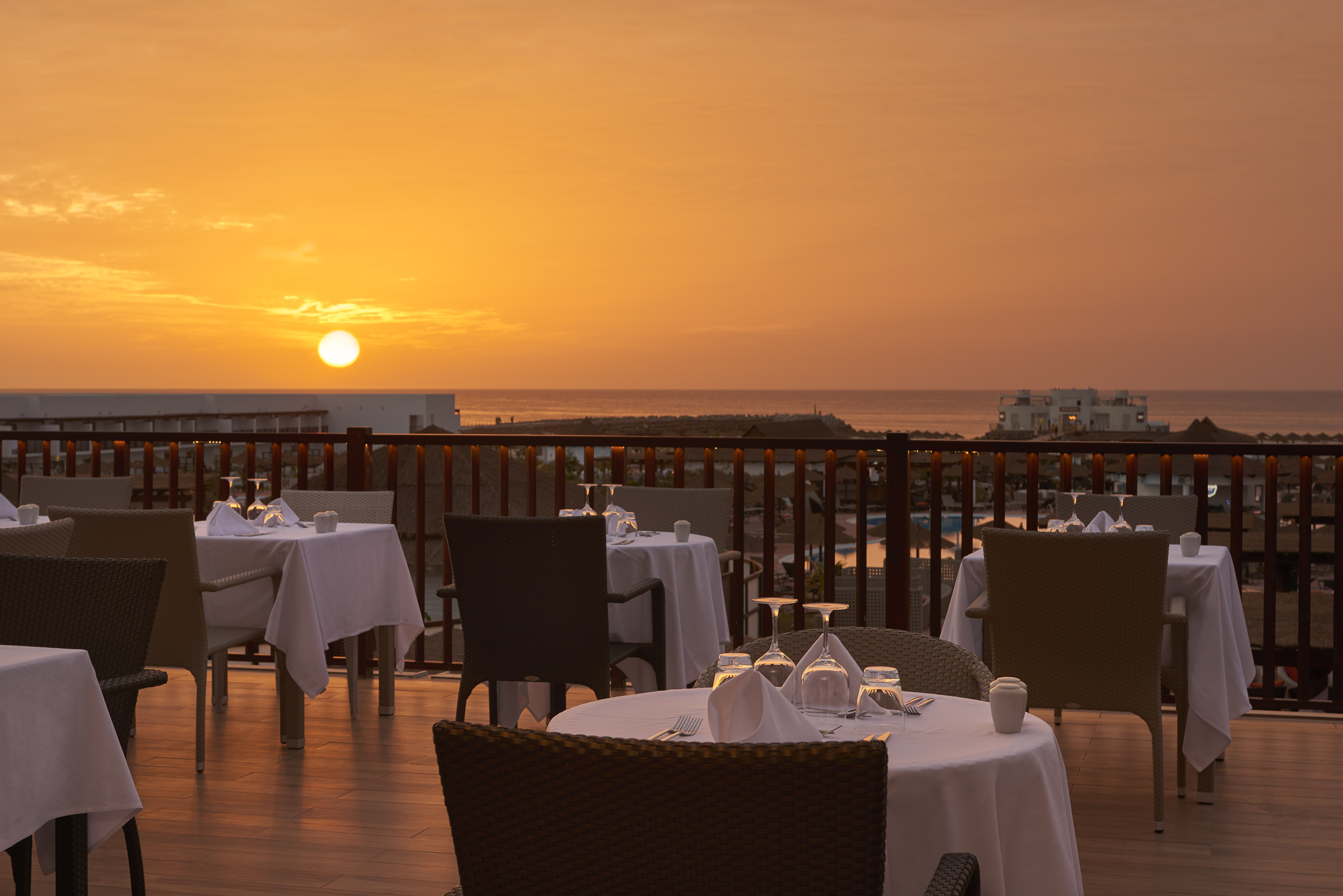a table set up on a deck with a sunset in the background