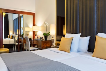 a bed with white sheets and pillows in a hotel room