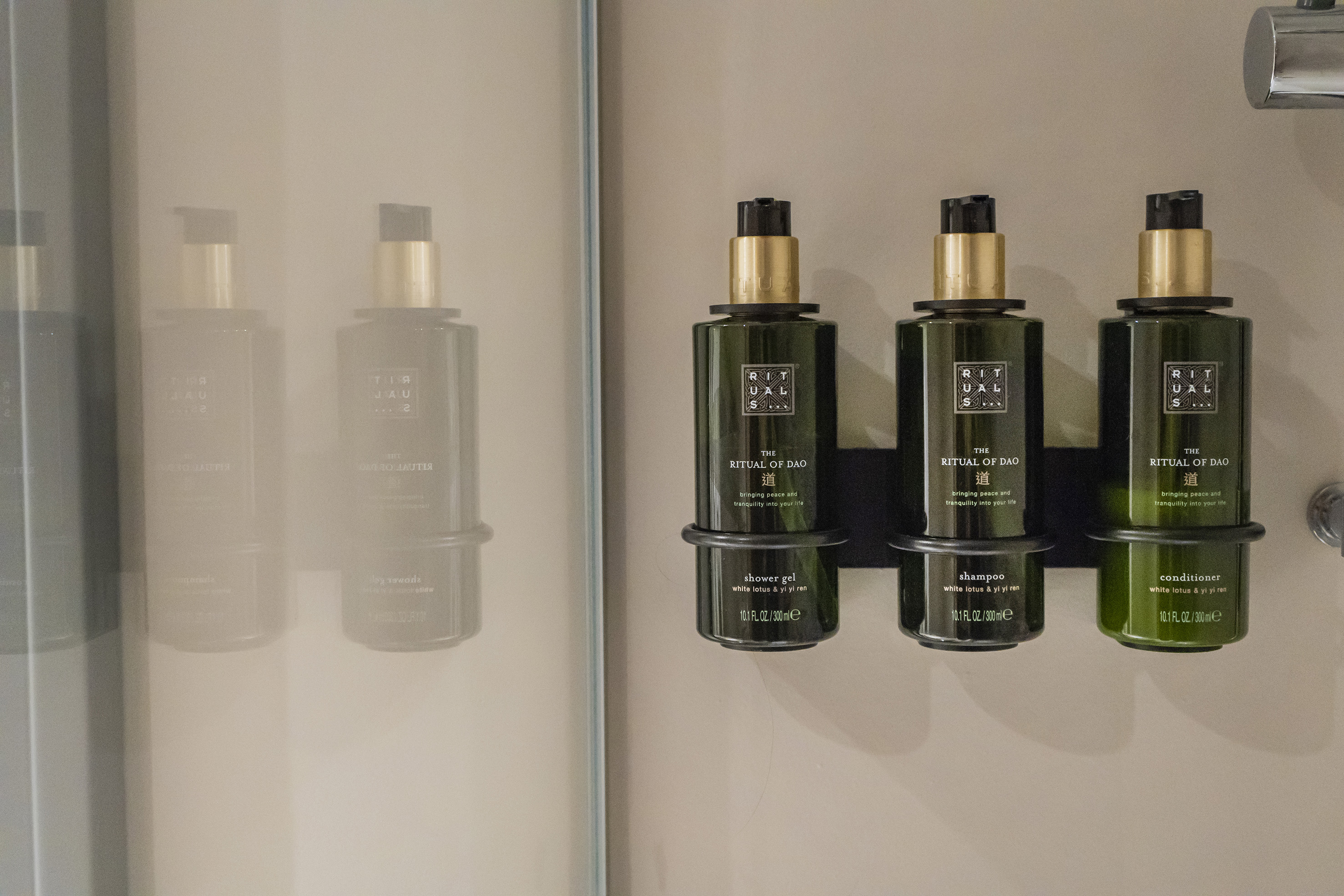 Rituals of Dao shower gel, shampoo, conditioner bottles in a shower.