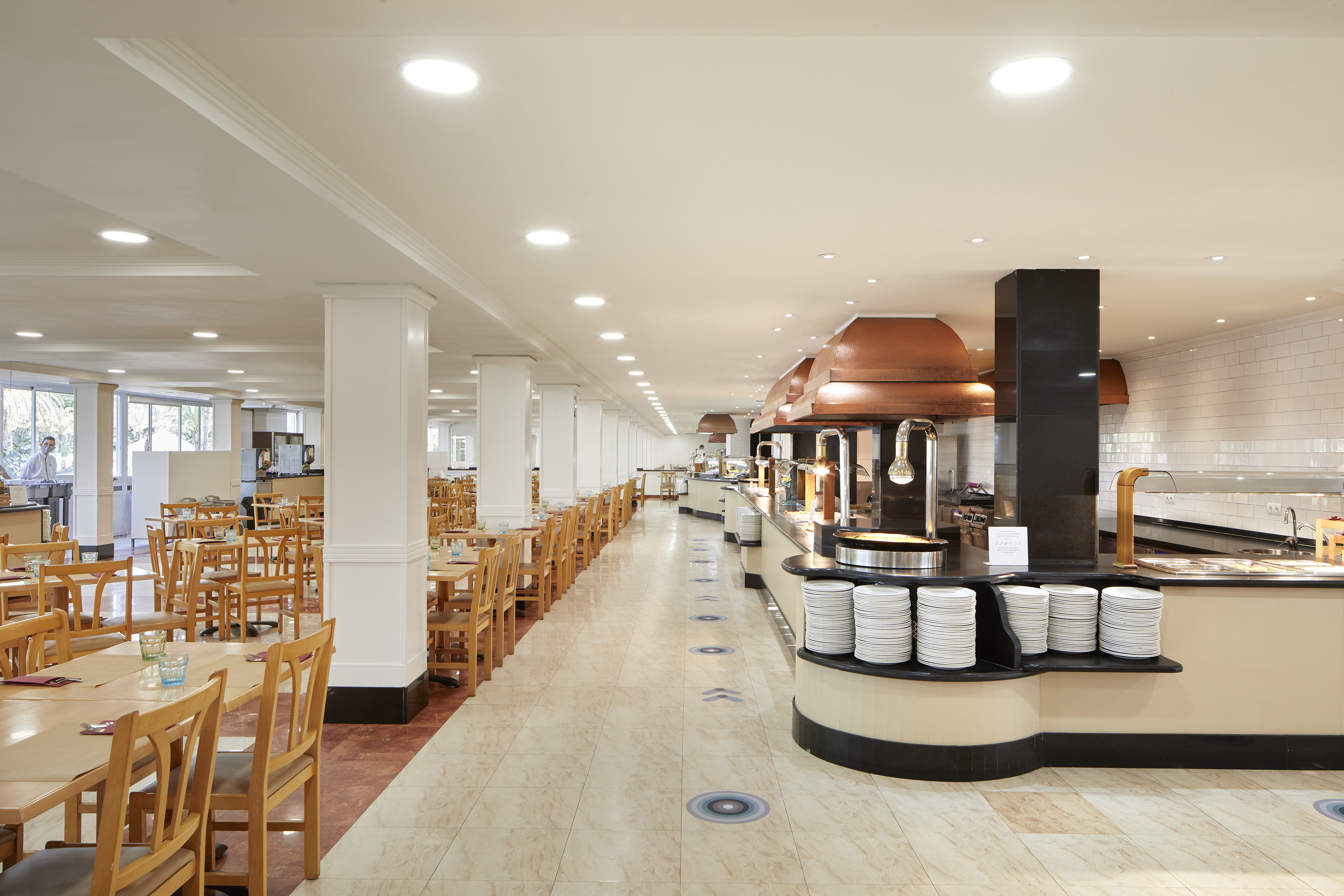 Spacious hotel buffet restaurant with food stations and dining tables.