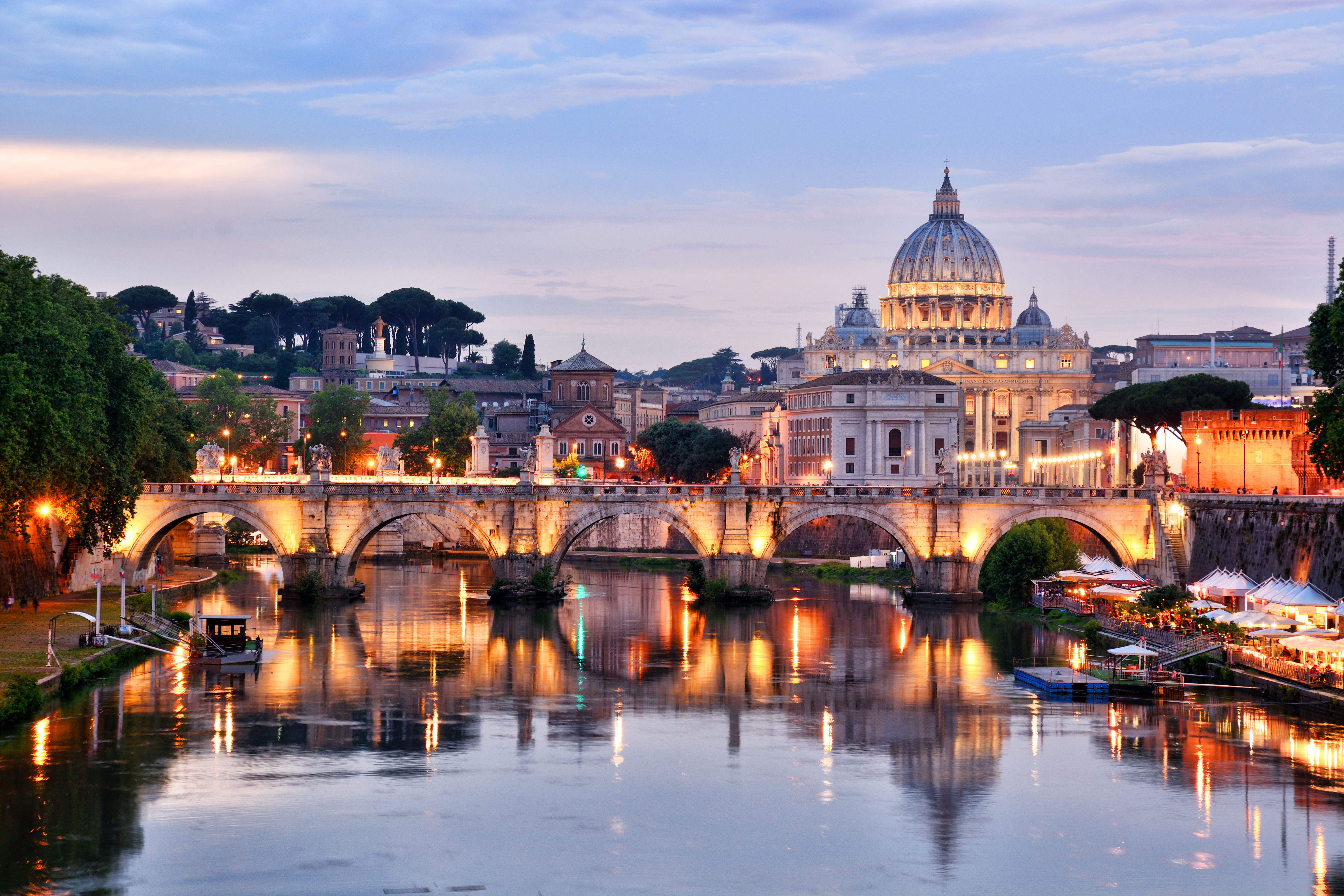 a bridge over a river with a dome and buildings in the background