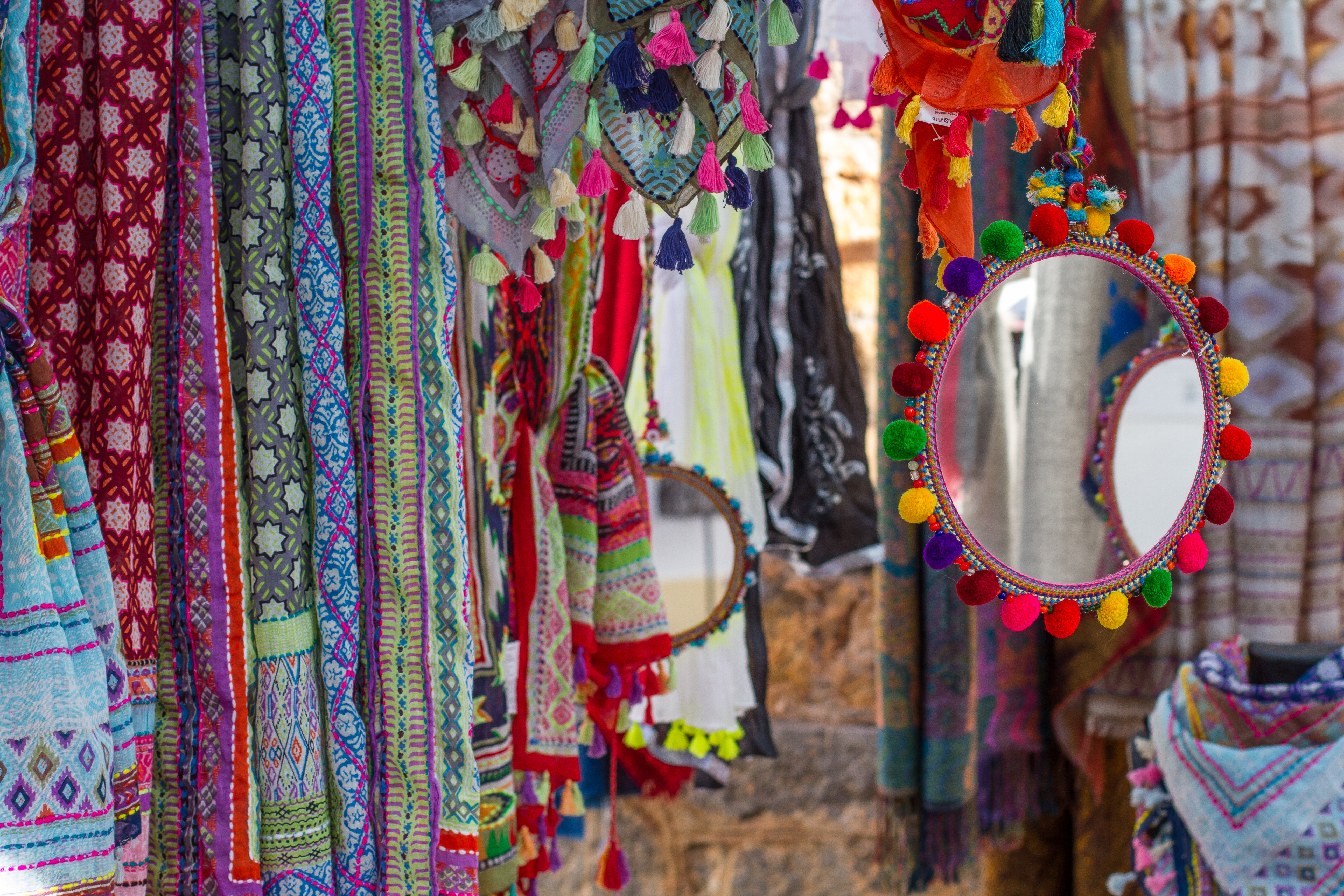 a group of colorful scarves and shawls from a wall