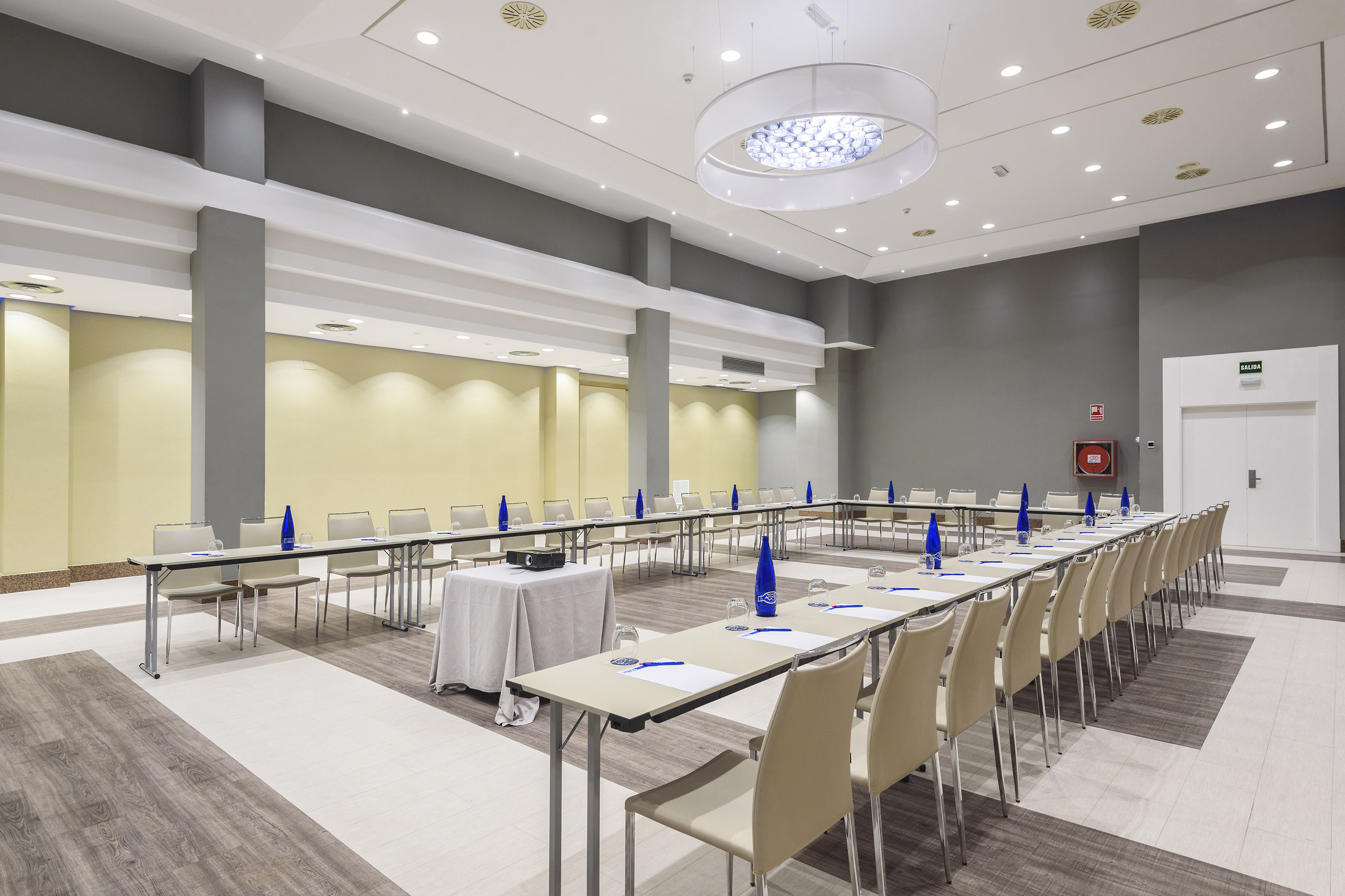 Empty modern hotel conference room with U-shaped table setup and projector.