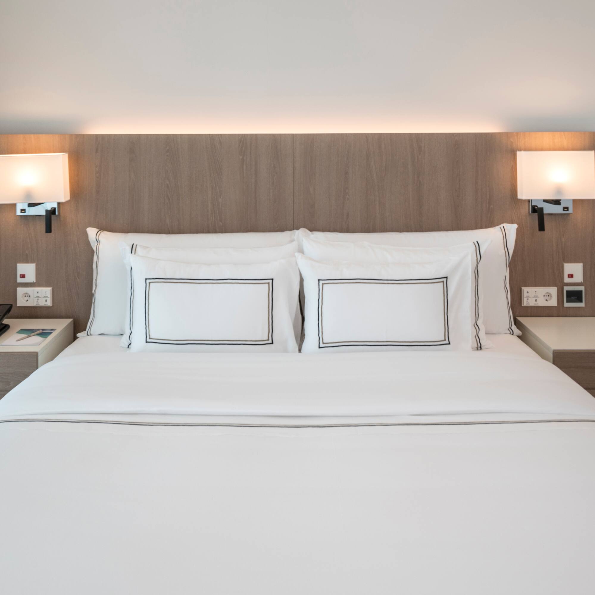 a bed with white sheets and a wood headboard