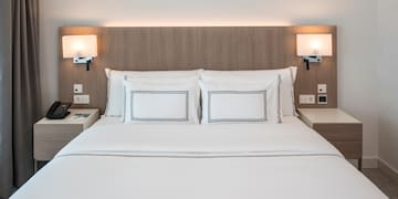 a bed with white sheets and a wood headboard