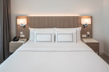 a bed with white sheets and a wood headboard