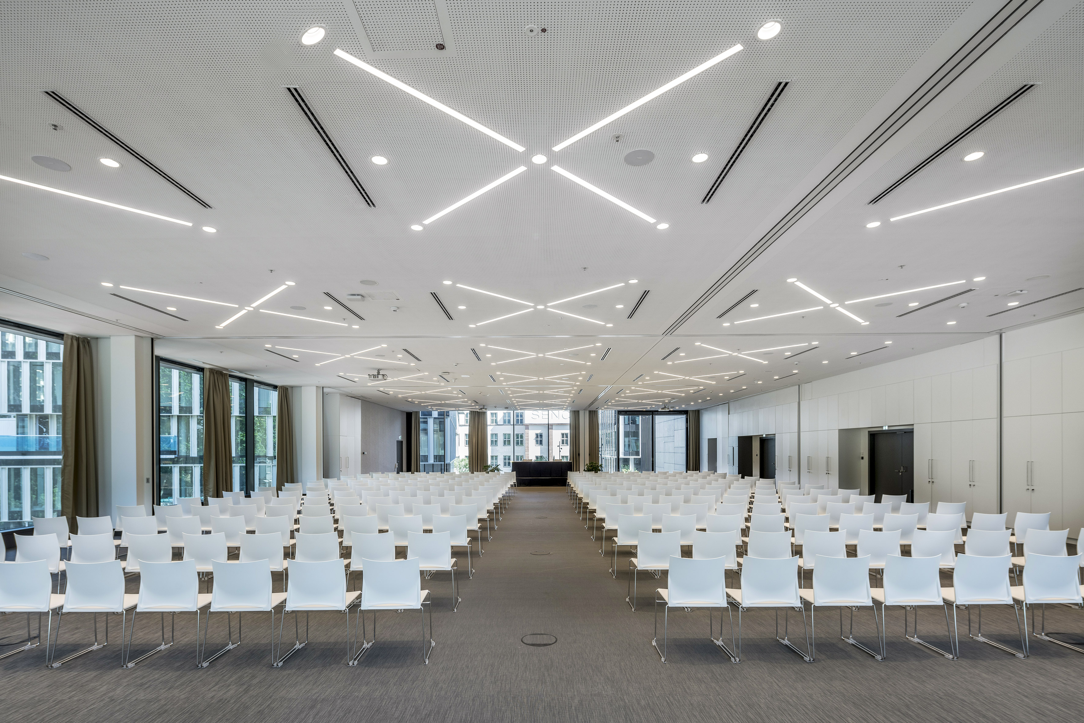 Modern empty conference room with white chairs and contemporary lighting.