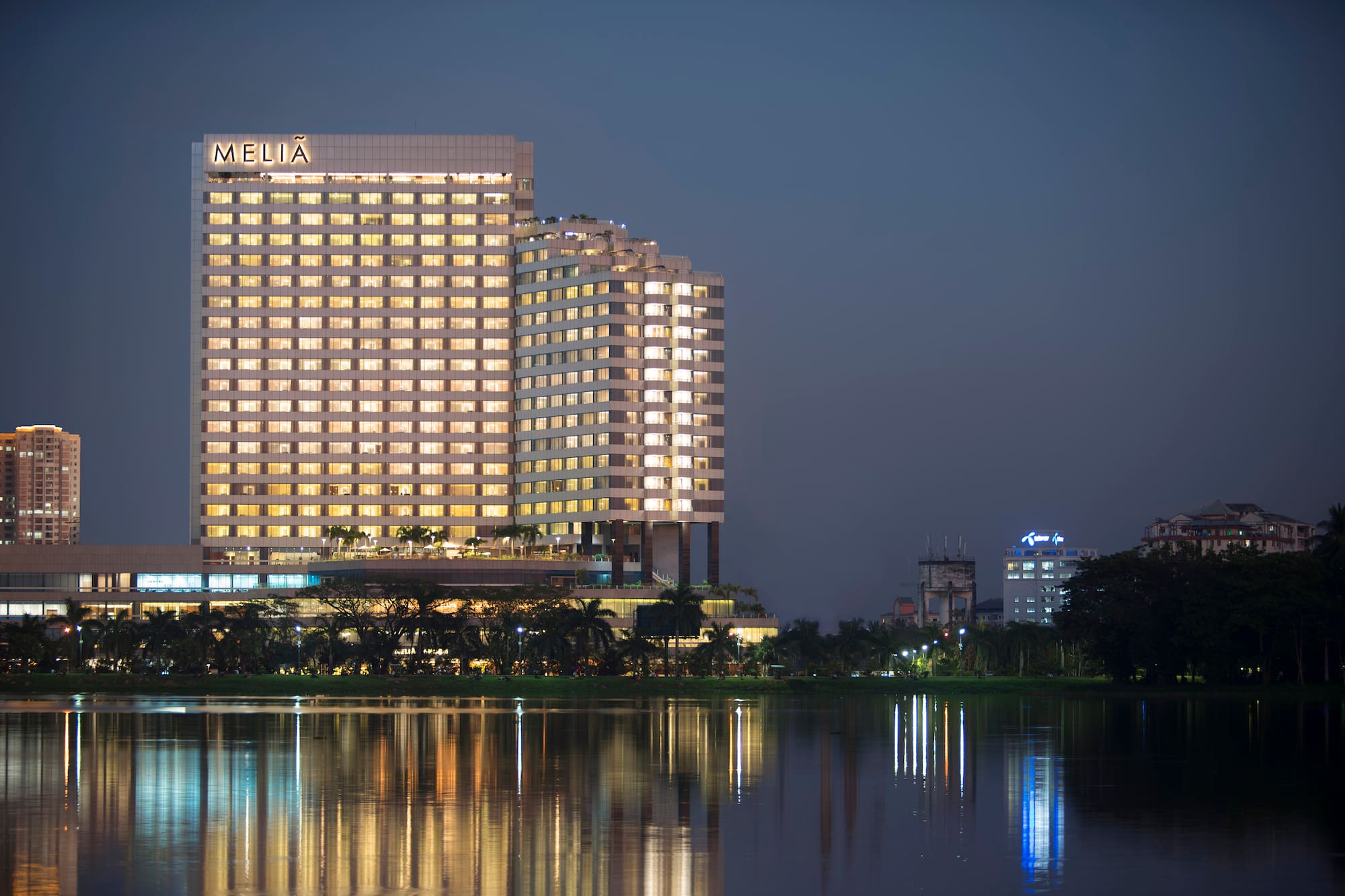 Meliá city hotel illuminated at night, reflected in a still lake.