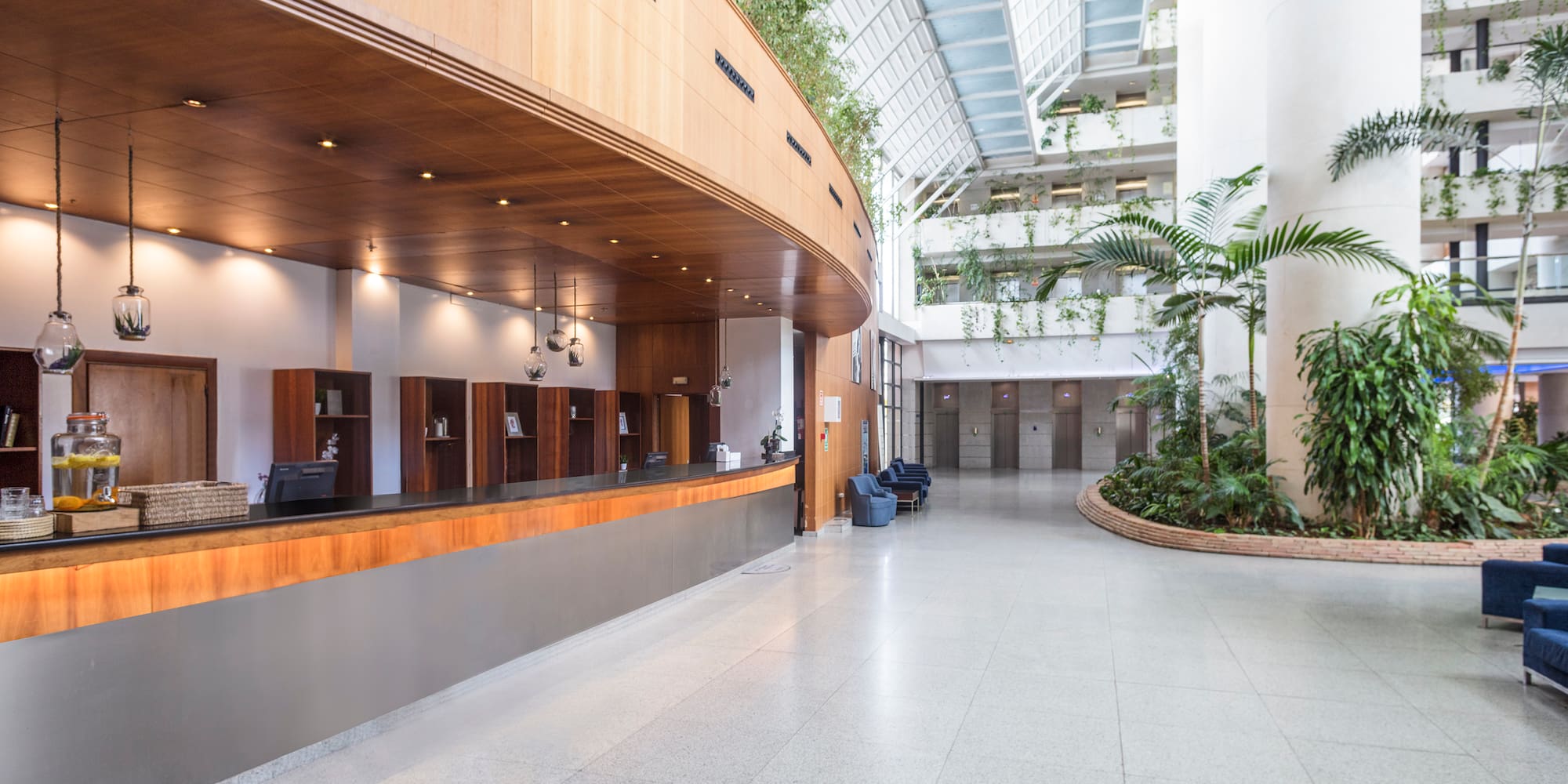 a lobby with a large building with plants and a large ceiling