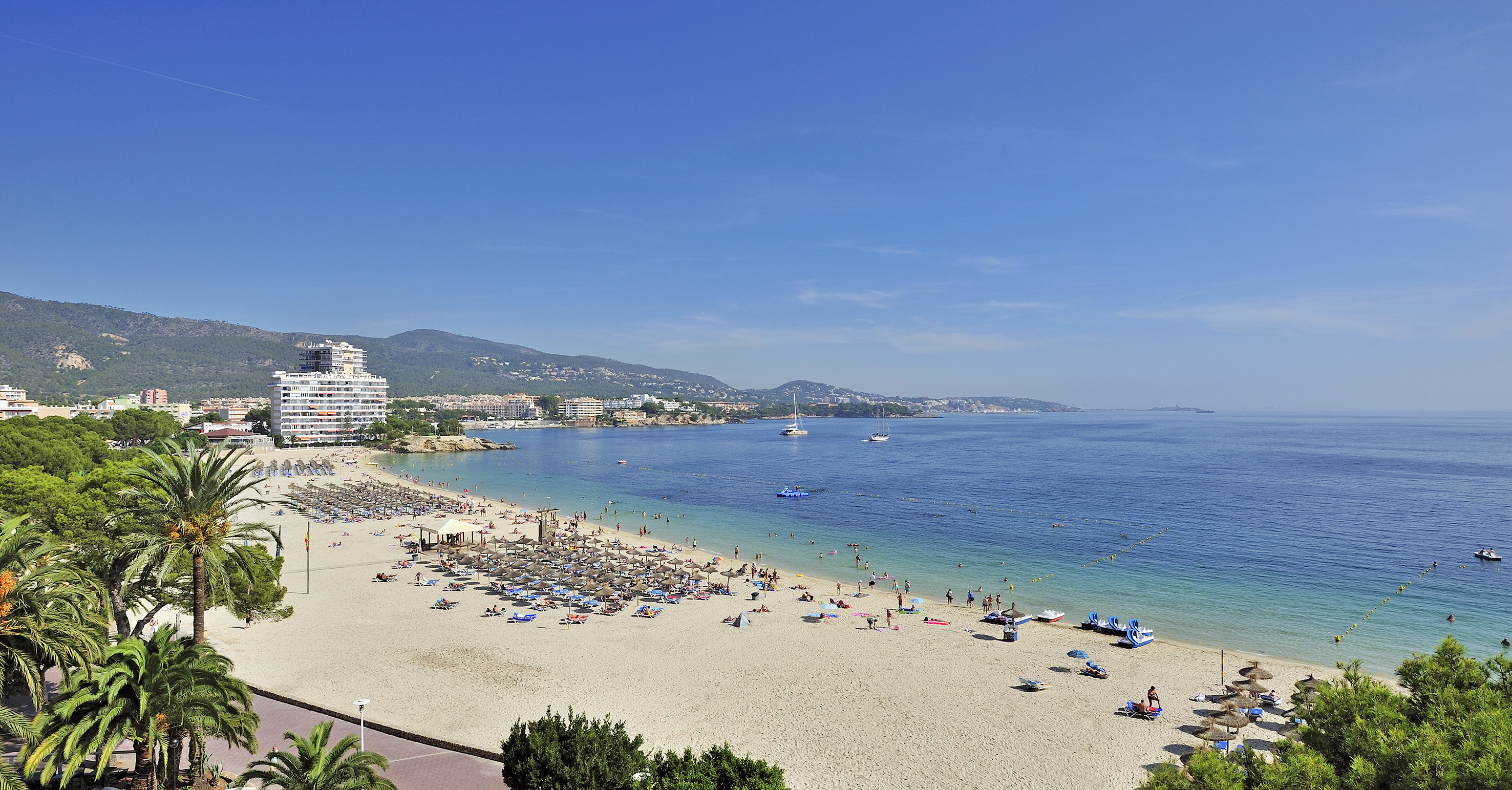a beach with people and boats on the water