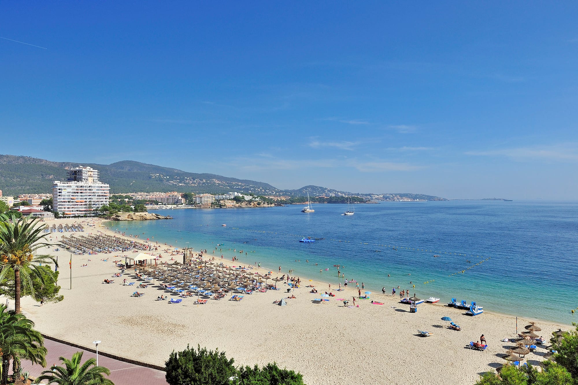 a beach with people and boats on the water