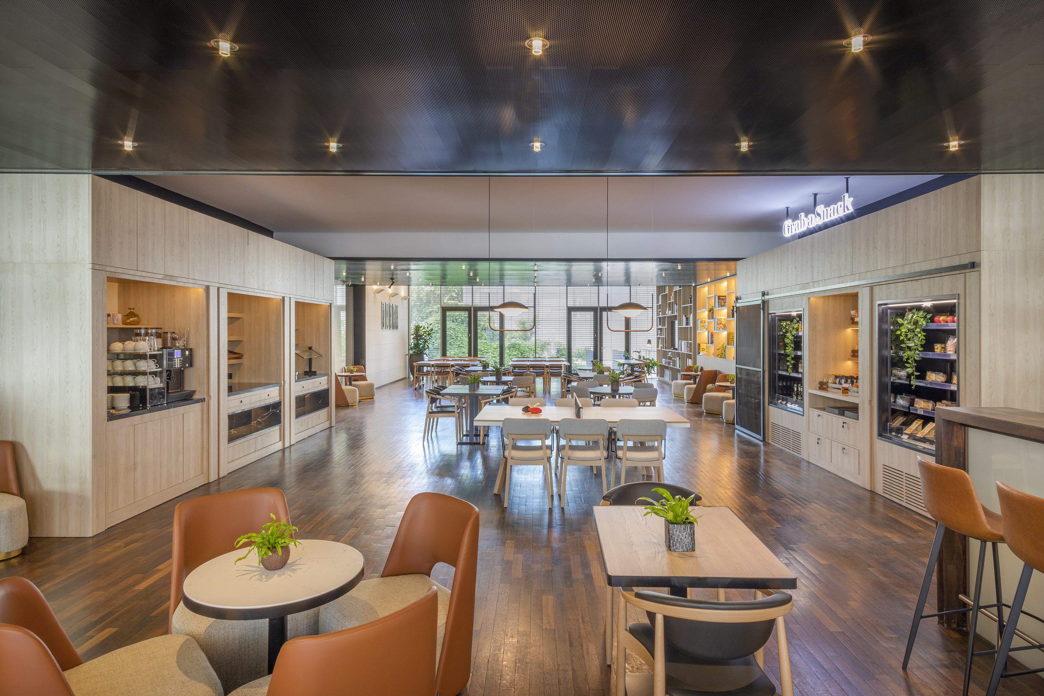 Modern cafe and lounge with varied seating, coffee bar, and grab-and-go snacks.