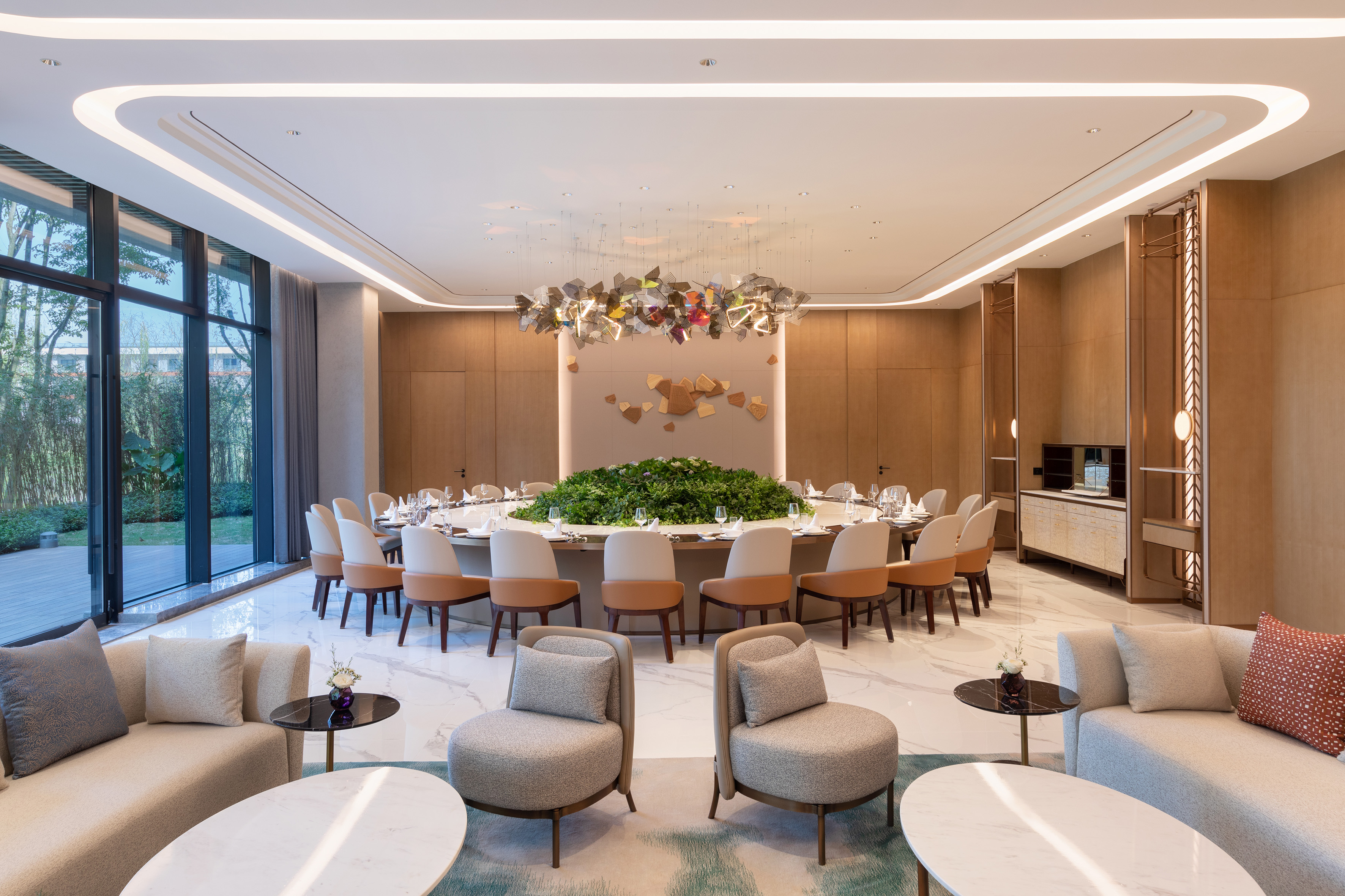 Luxury private dining room with round table, modern chandelier, and lounge area.