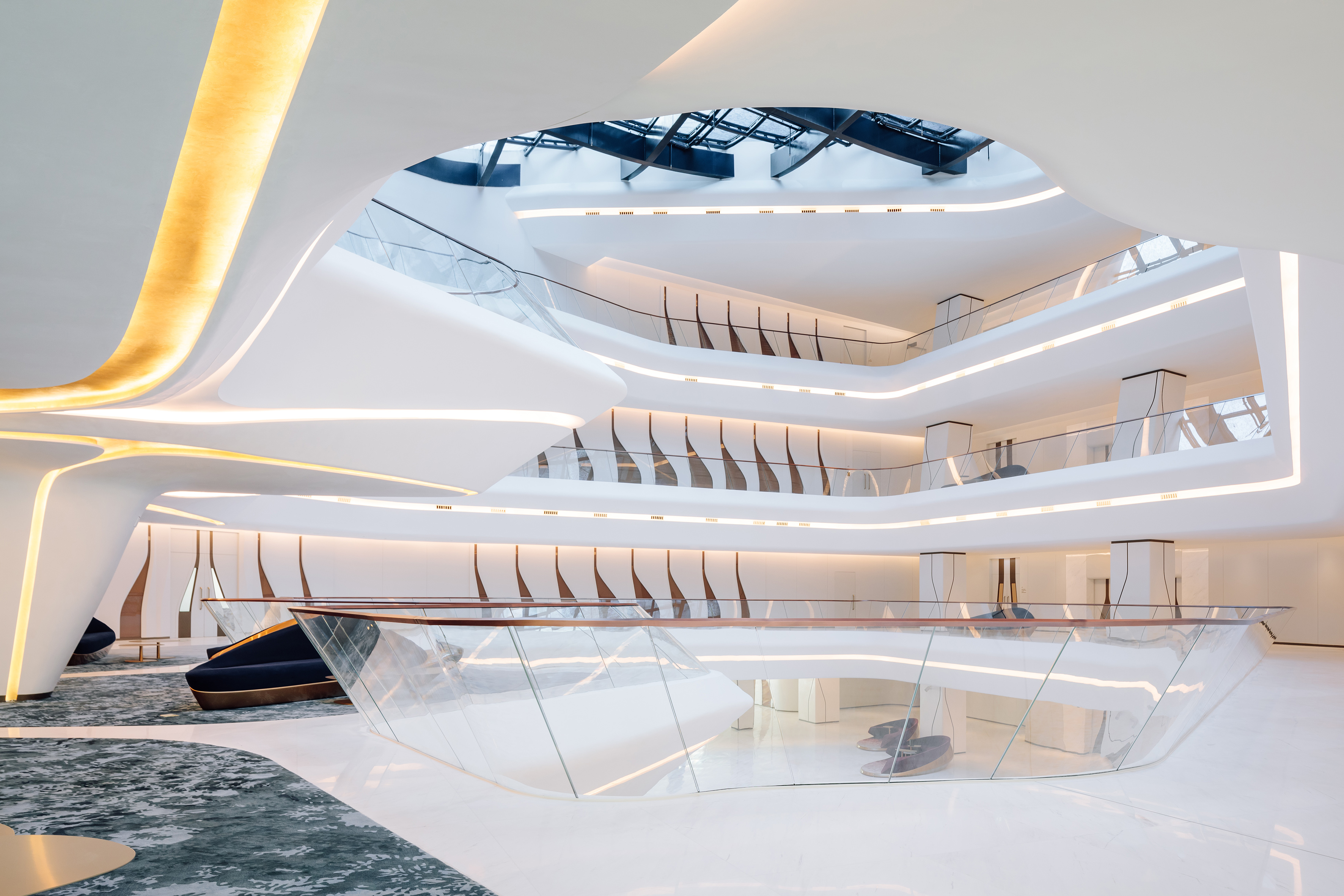 Modern luxury lobby with curved white architecture, golden lighting, and glass railings.