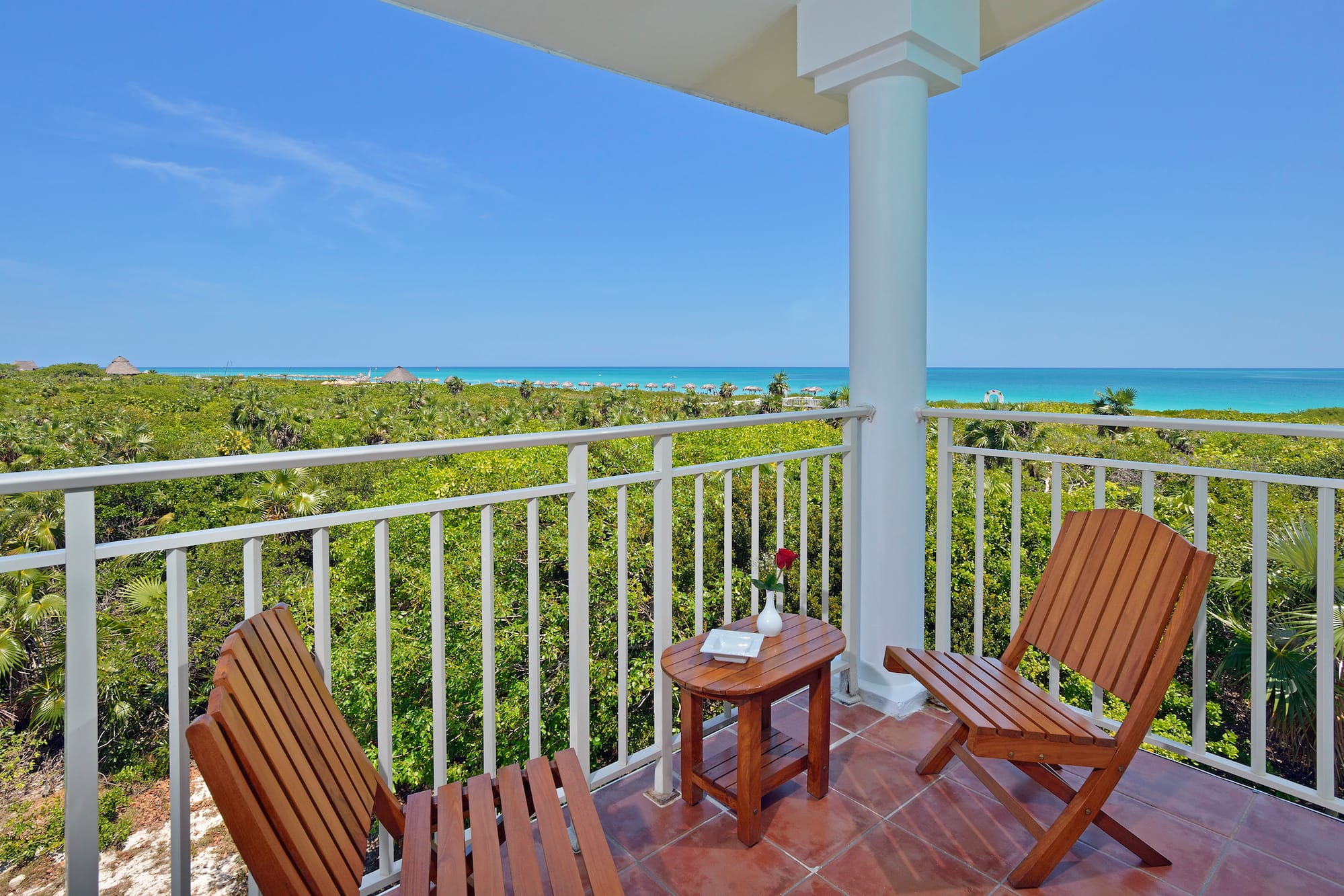 a deck with chairs and a table overlooking a beach