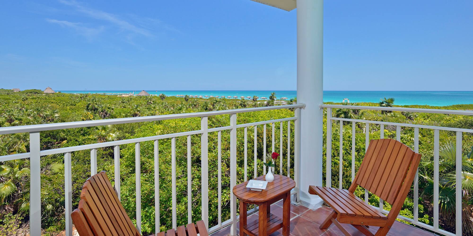 a deck with chairs and a table overlooking a beach