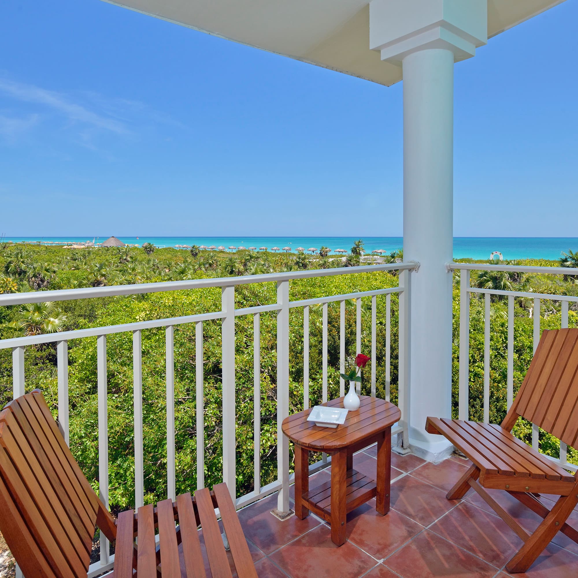 a deck with chairs and a table overlooking a beach