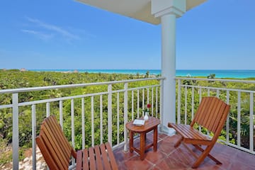 a deck with chairs and a table overlooking a beach