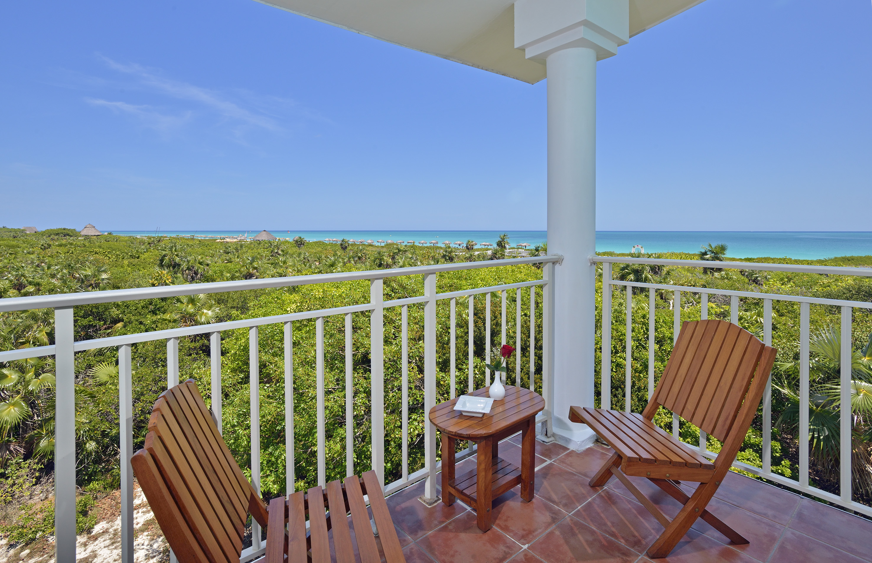 a deck with chairs and a table overlooking a beach