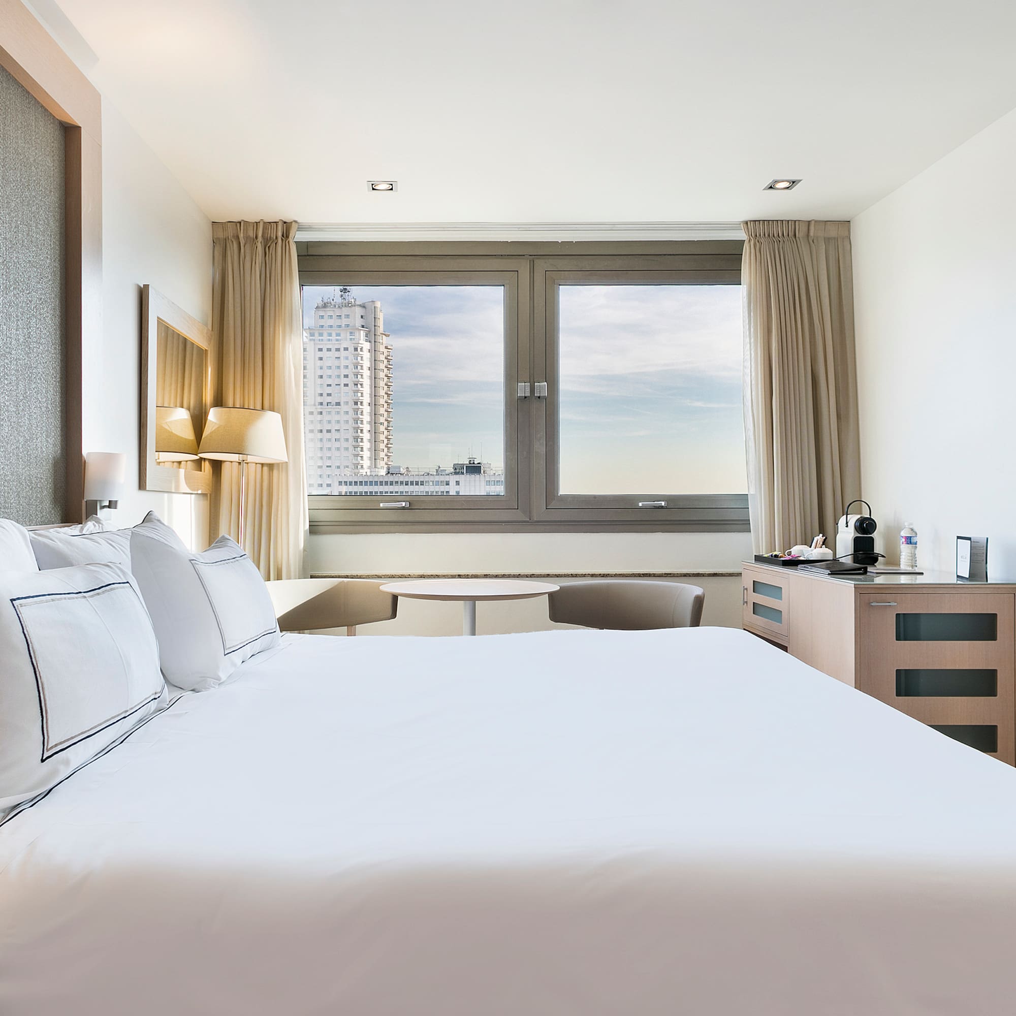 a bed with white sheets and pillows in a hotel room