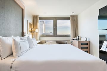 a bed with white sheets and pillows in a hotel room