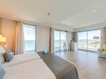 a room with two beds and a large window overlooking the ocean