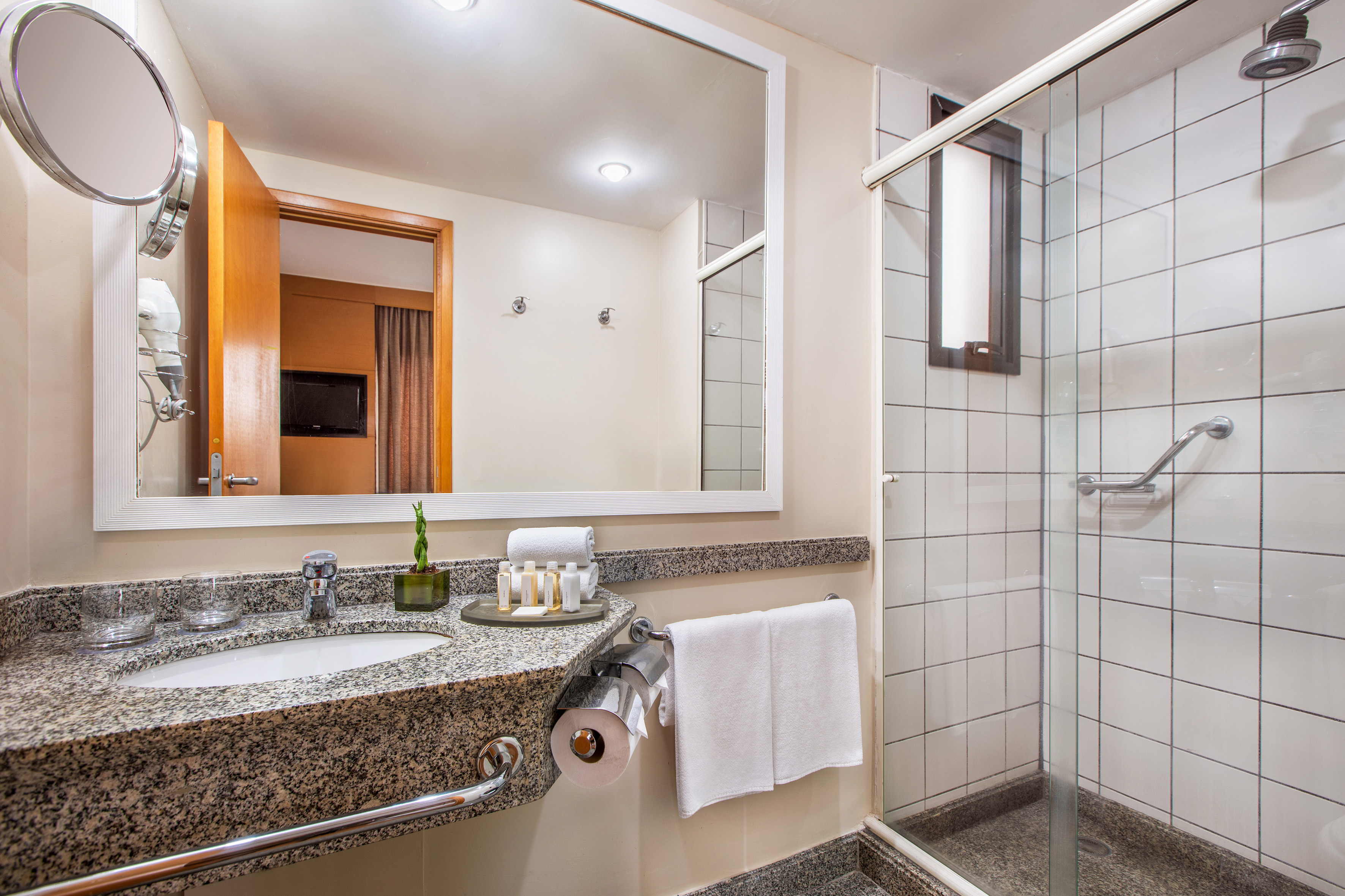 Clean bathroom with granite vanity, white sink, mirror, and walk-in shower.