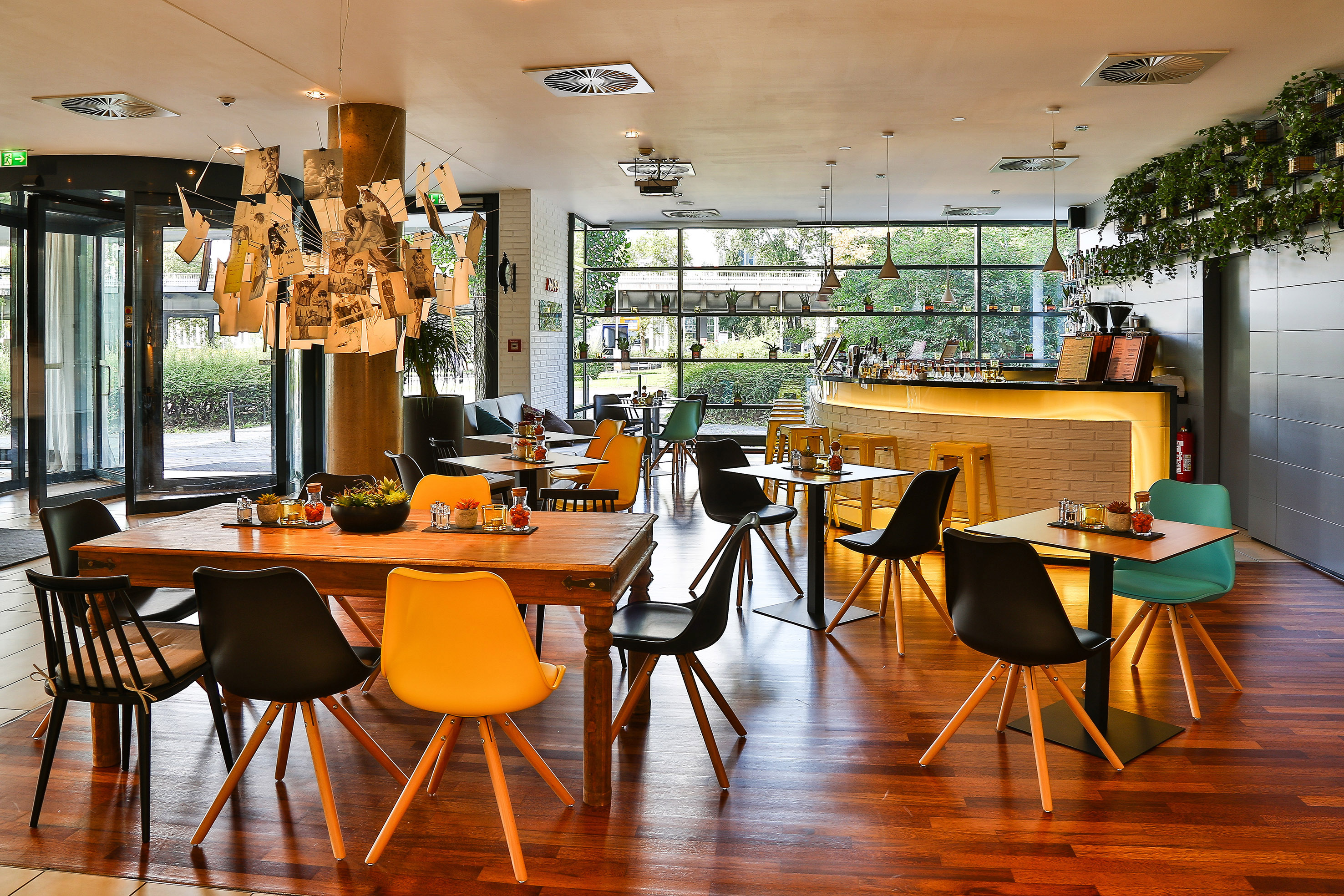 Stylish restaurant interior with colorful seating, wooden floors, and an illuminated bar.