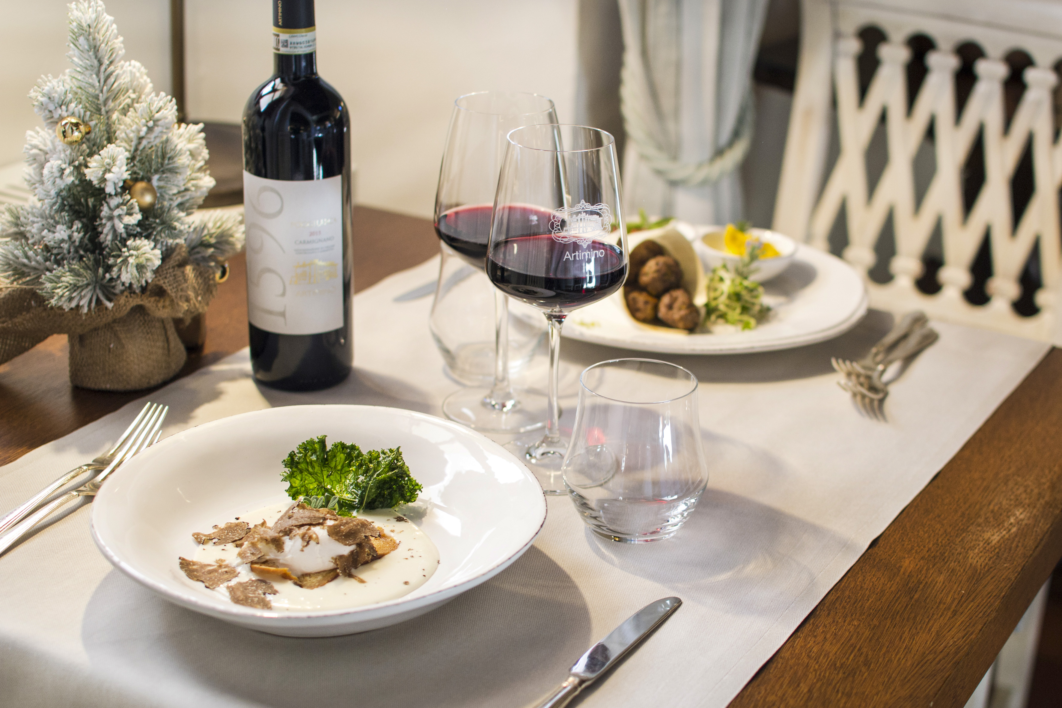 Festive dinner table with Artimino red wine, truffle dish, and Christmas decor.