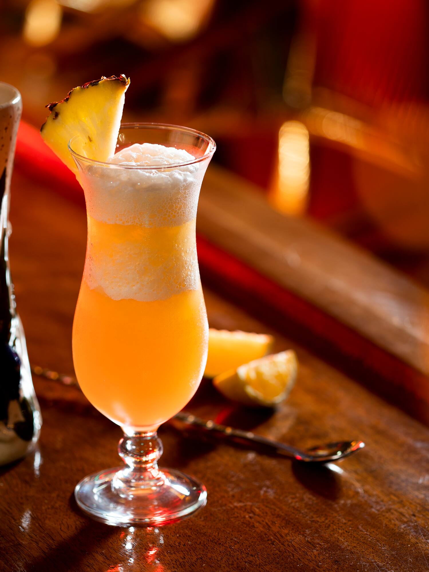 a glass of orange liquid with a slice of pineapple on top of it