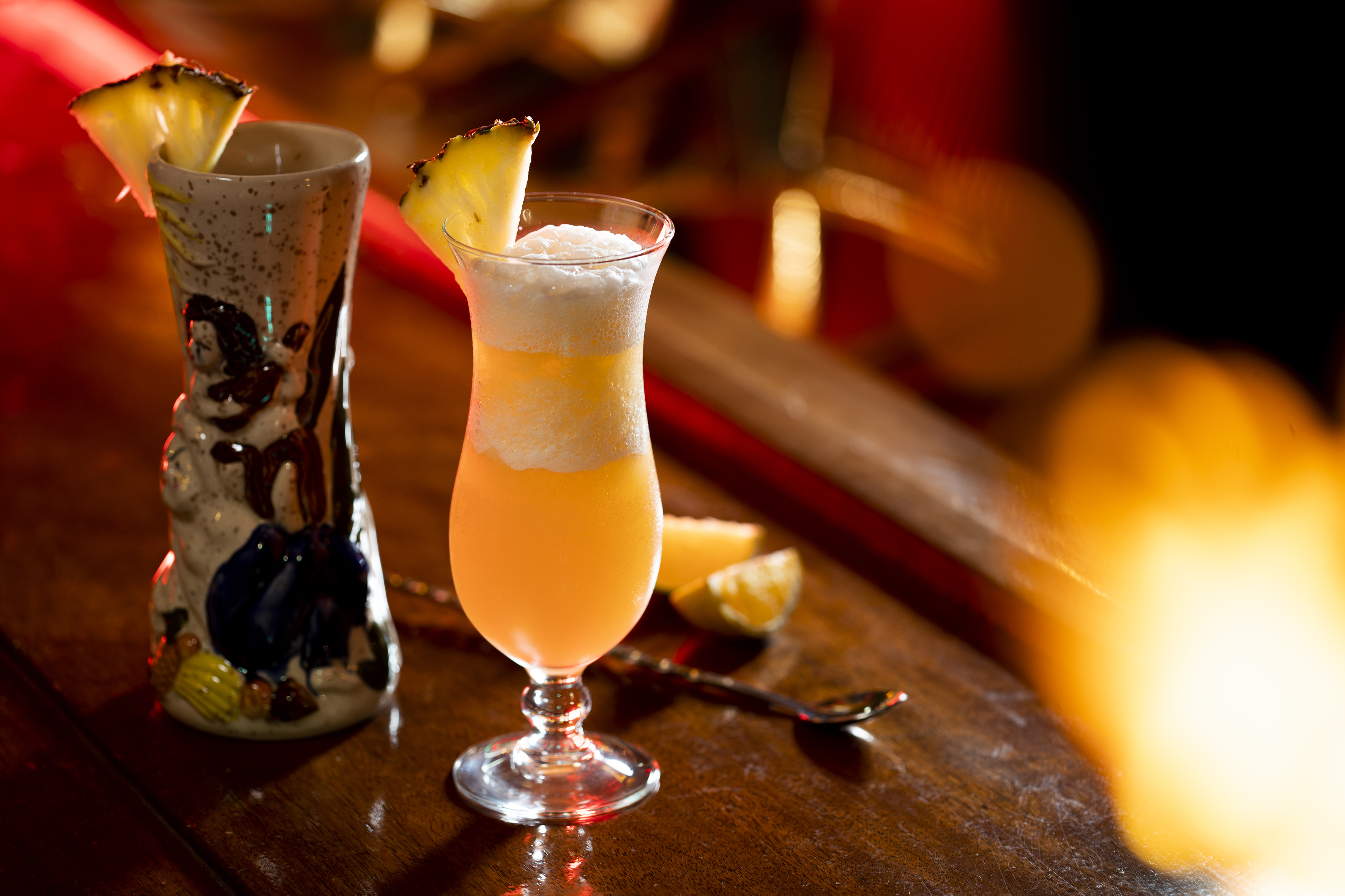 a glass of orange liquid with a slice of pineapple on top of it