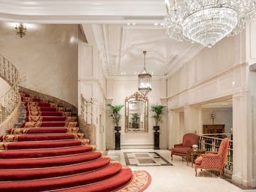 a staircase with red carpet and chandelier