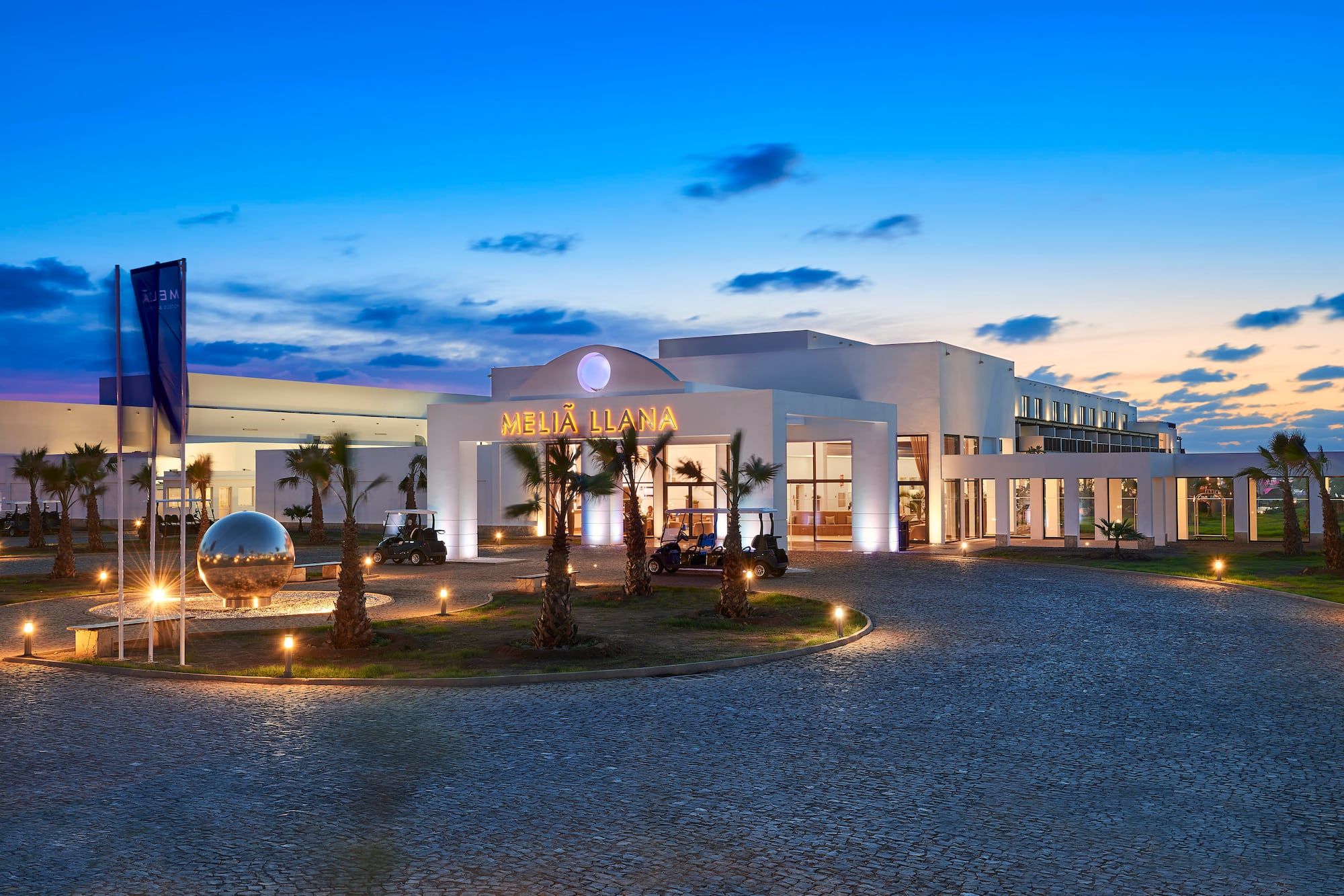 a building with palm trees and a round driveway