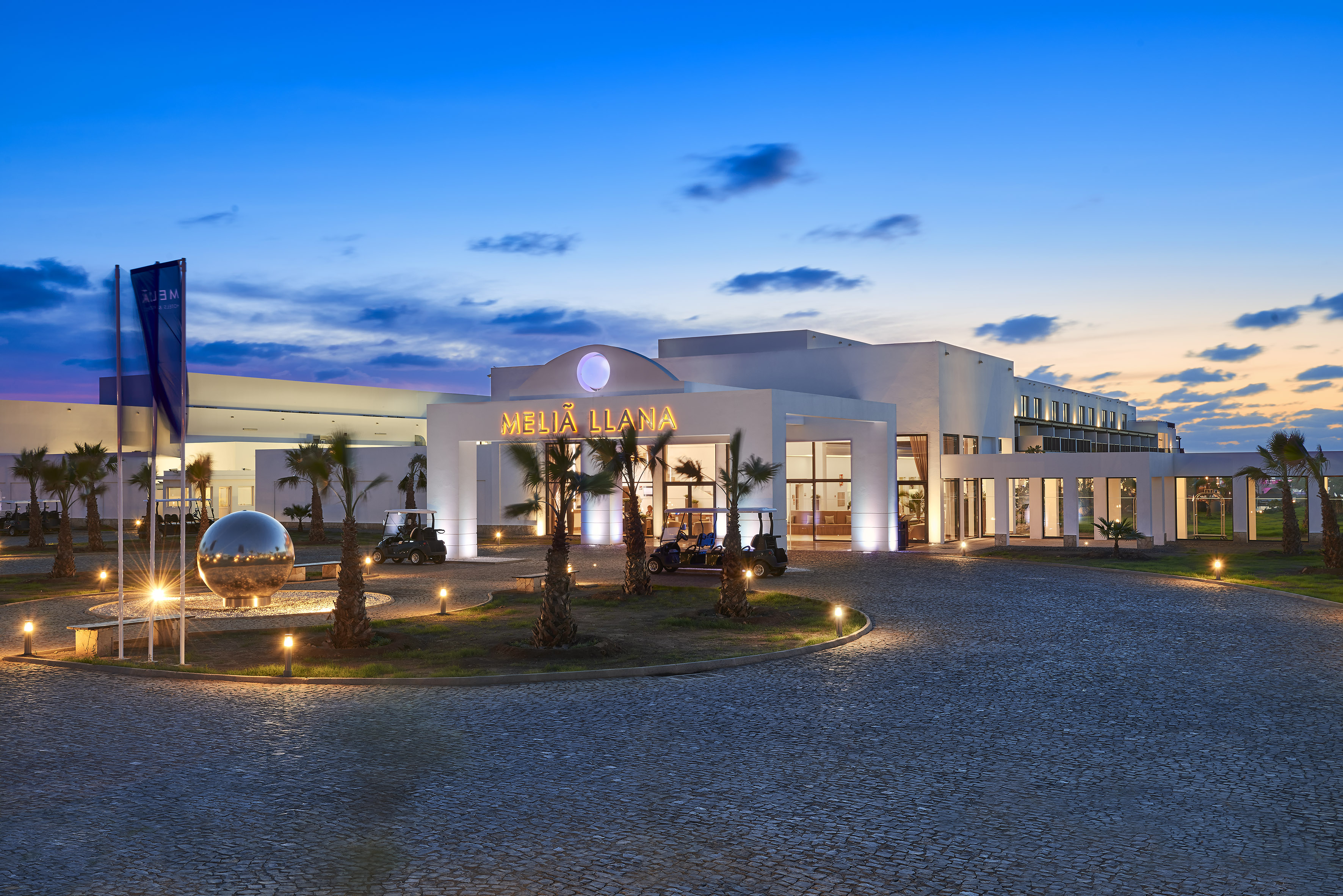 a building with palm trees and a round driveway