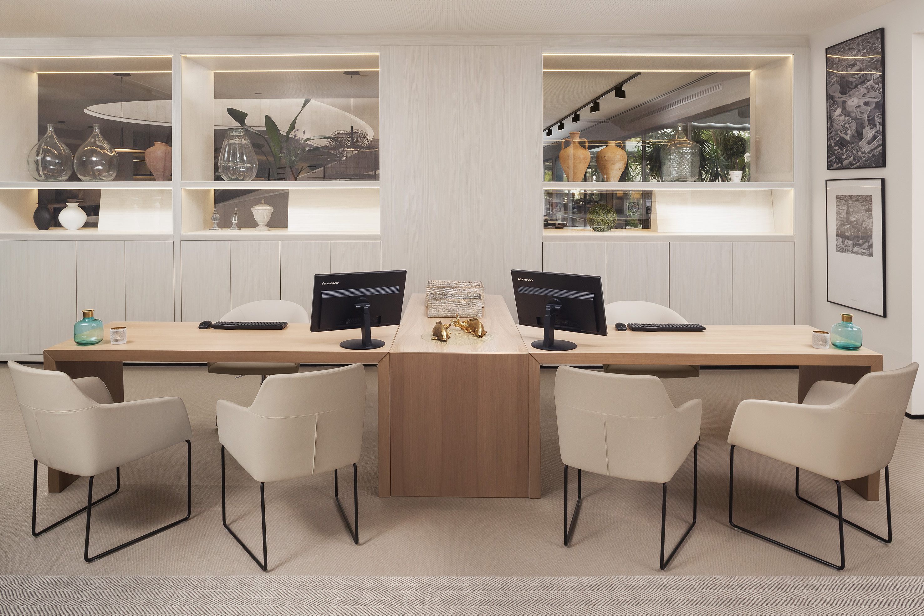 Modern reception area with light wood desk, computers, and cream chairs.