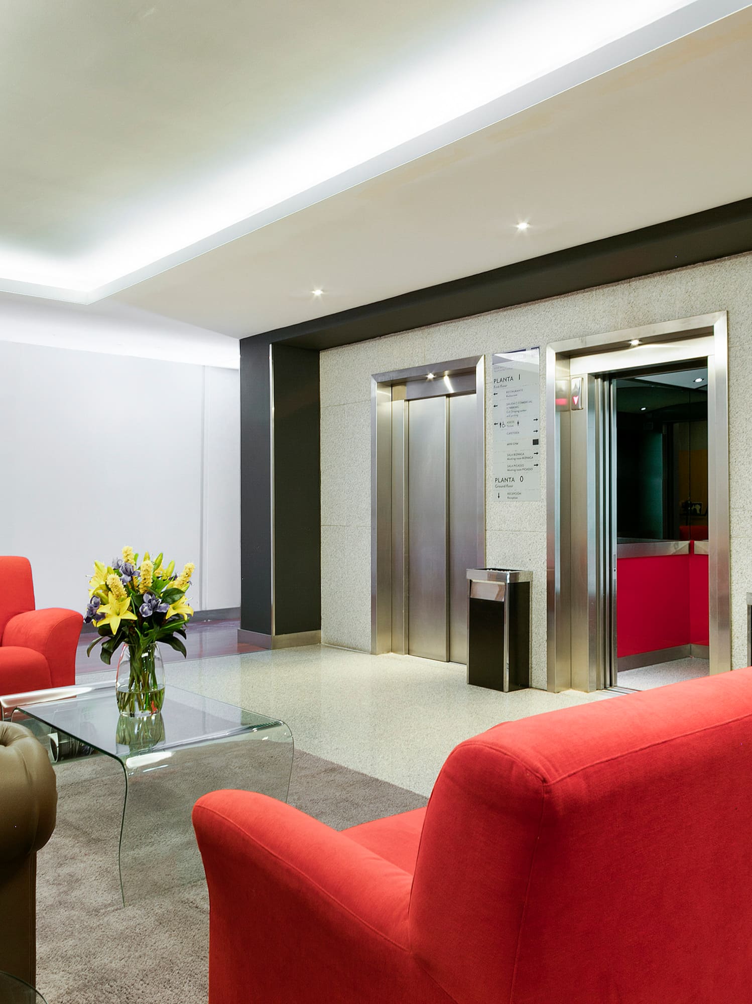 a lobby with red chairs and a glass coffee table