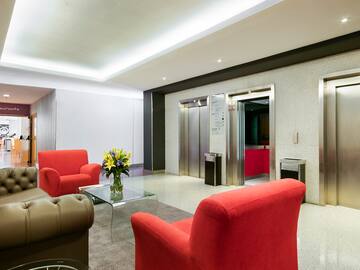 a lobby with red chairs and a glass coffee table