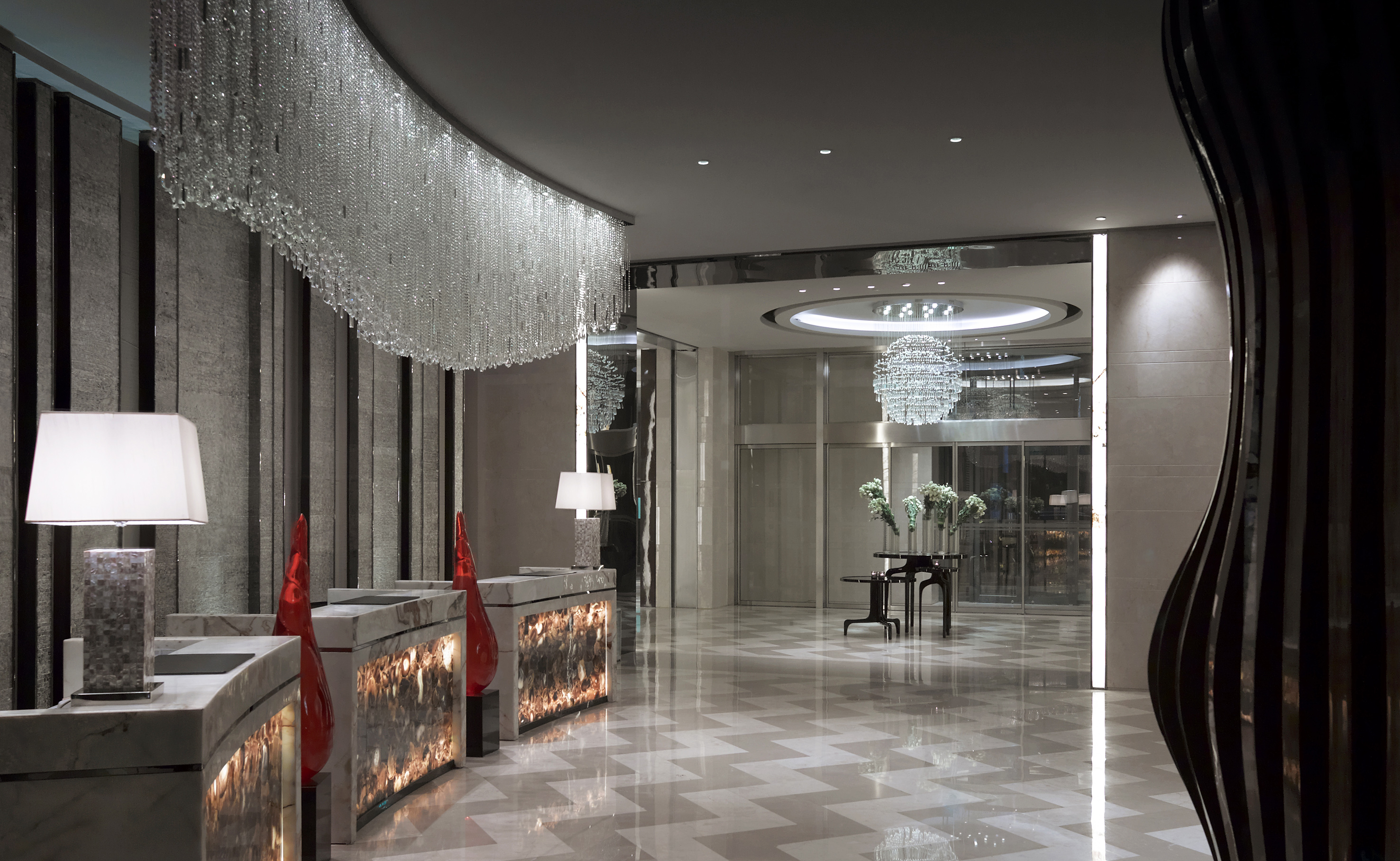 Luxury hotel lobby with crystal chandeliers, marble reception desks, and geometric floor.