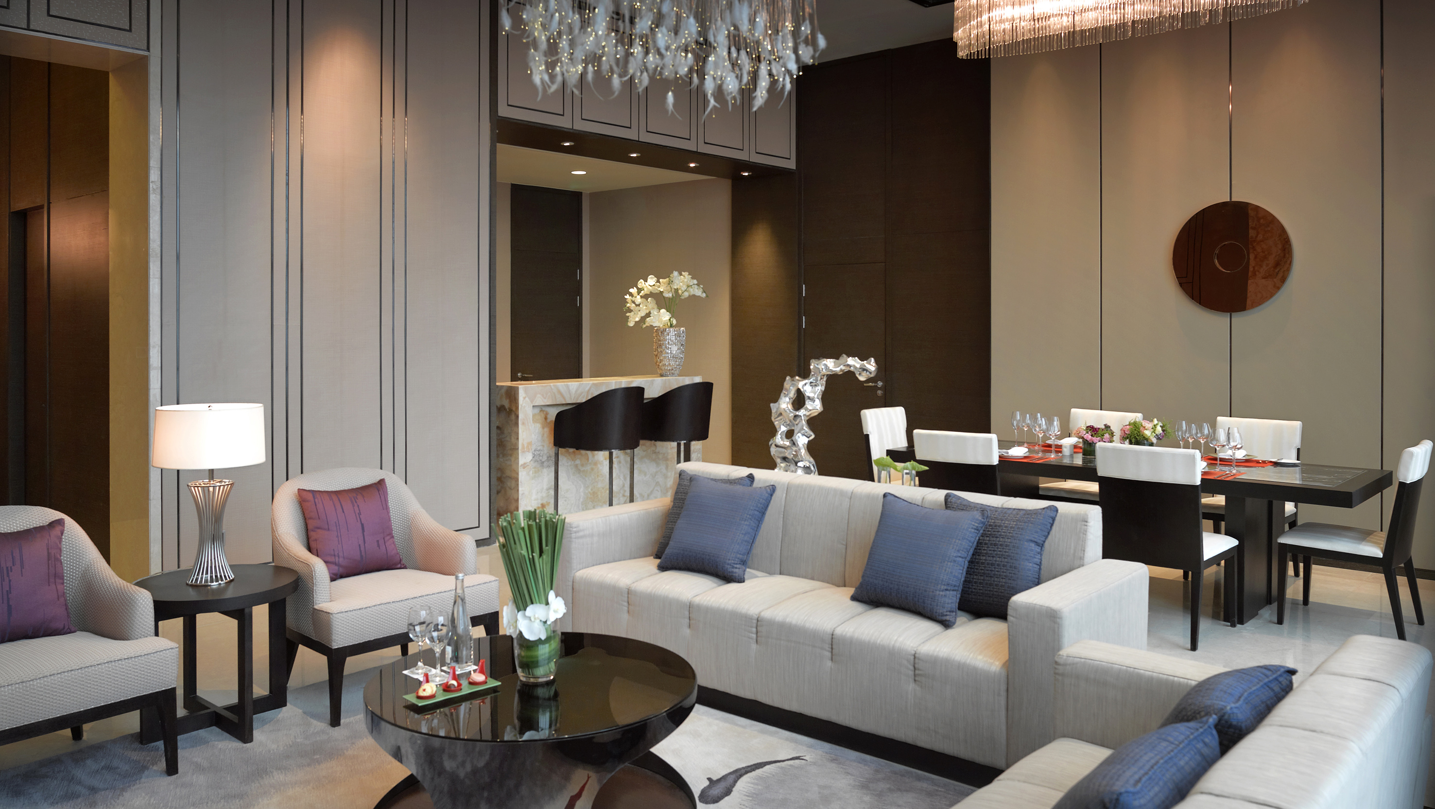 Modern luxury living and dining room with bar, sofa, and chandelier.